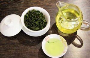 Freshly brewed Tieguanyin tea with gaiwan, fairness pitcher, and a tasting cup on a wooden table